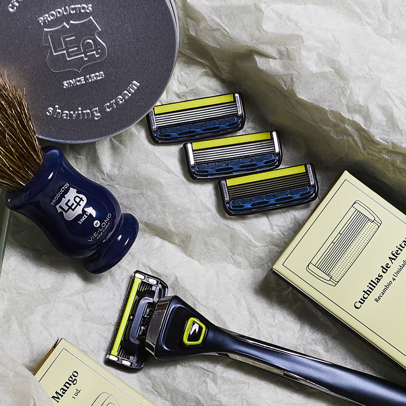 Image of razor with blades and shaving cream on white paper background.