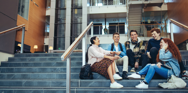 Group of people sitting on stairs having conversation.