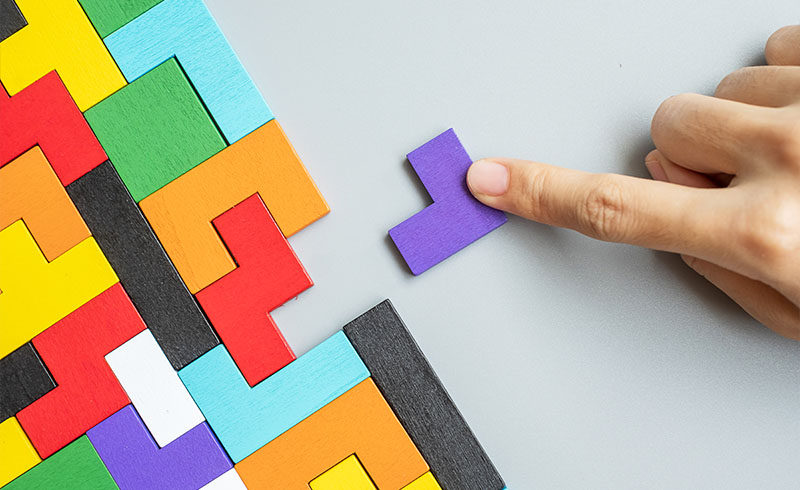 A hand of person completing a colorful puzzle.