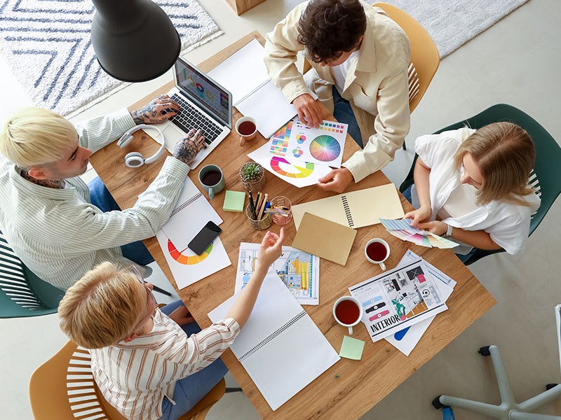 Team of graphic designers working with color palettes at table in office