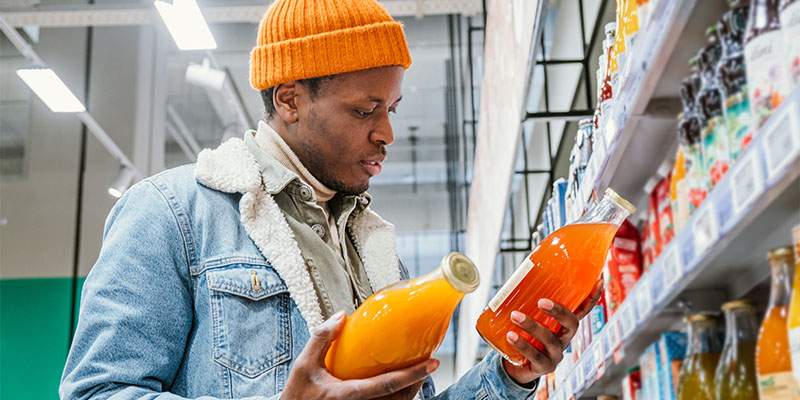 A man holding two bottles of juice reading the labels.